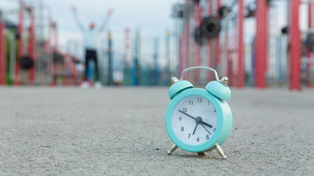 The alarm clock on the sports ground, in the background a blurred silhouette of a man.の写真素材
