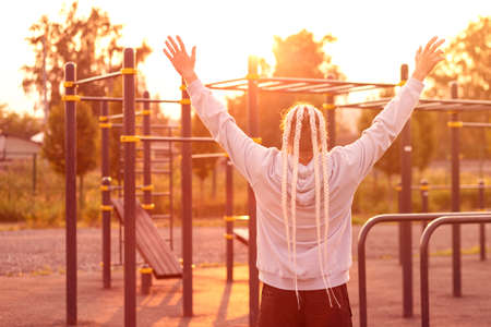 In the morning at sunrise, a man with an interesting braid hairstyle triumphantly raised his hands...