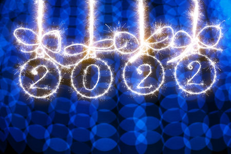 Christmas balls made of sparklers and the inscription 2022 on a blue blurred background of New Years lightsの写真素材