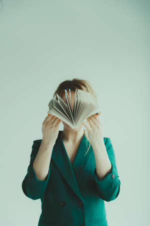 Young blond woman covering her face with a book.の写真素材