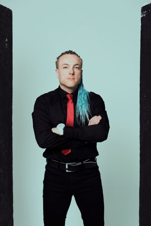 Young attractive man with an interesting haircut in braids on an undercut with a red tie on a light background.の写真素材
