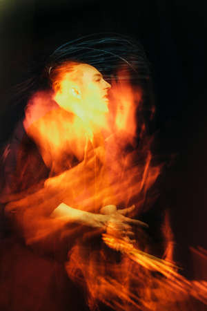 Handsome man with interesting braids on a black background with drumsticks, shot with mixed light.