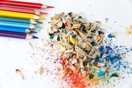 Colored watercolor pencils of rainbow colors and shavings from them after sharpening on a white backgroundの写真素材