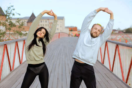 A man and a woman prepare for a bridge run and do a stretching exercise.の写真素材