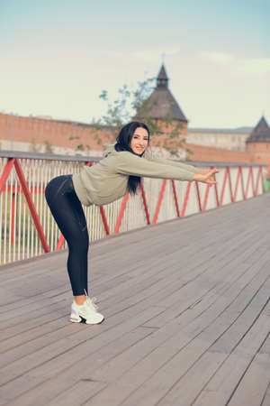 A woman in sweatshirt on the bridge stretches before training.の写真素材