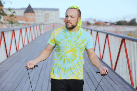 A young man in sportswear is jumping on jump ropes on bridge.