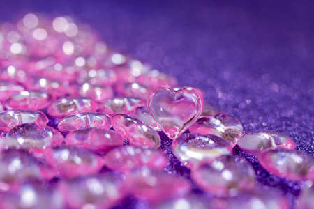 Pink transparent plastic hearts on purple glittering backgroundの写真素材