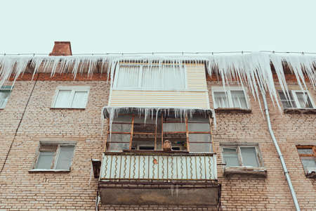Russia. Terrible huge icicles formed on the roof peak and balconies of a multi-storey building due to a poor roof storm system.の写真素材