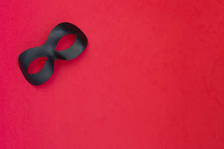 Black carnival mask on a light red backgroundの写真素材