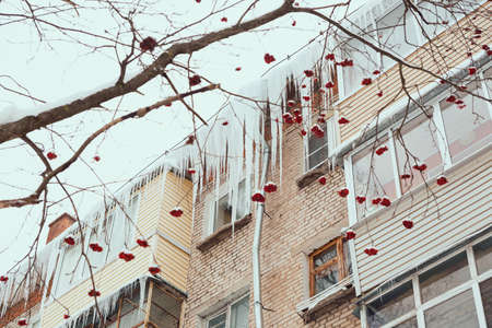 Russia. Terrible huge icicles formed on the roof peak and balconies of a multi-storey building due to a poor roof storm system.の写真素材