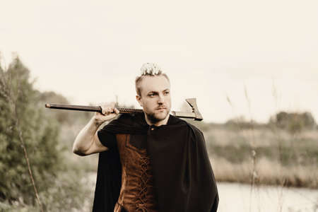 A young man with an interesting depicts a Viking with an ax in an unreliable stylized modern costume.の写真素材