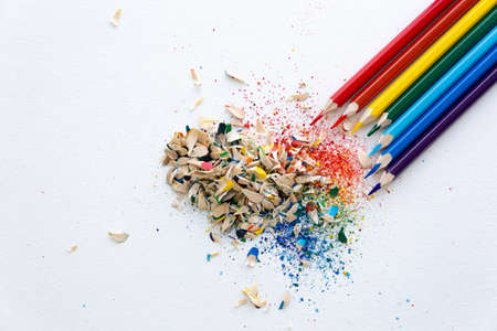 Colored watercolor pencils of rainbow colors and shavings from them after sharpening on a white background.の写真素材