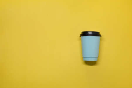 Paper cup with coffee on a yellow background on the right.の写真素材
