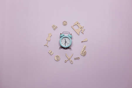 A small green alarm clock on a purple background surrounded by kitchen items. Time to cook.の写真素材