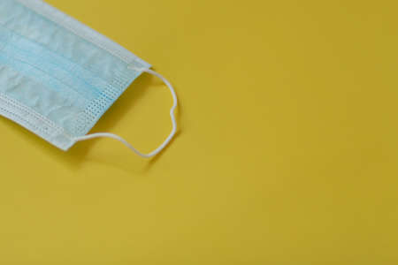 Medical three-layer mask on a yellow background.