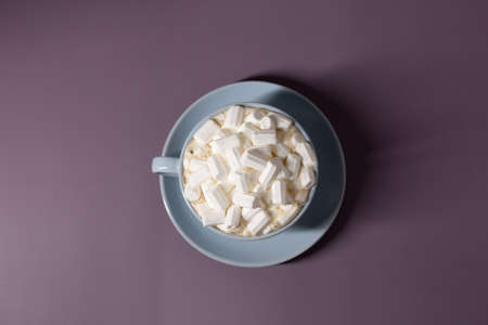 Blue cup of coffee with marshmallows on a purple background.の写真素材