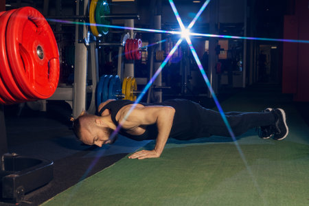 A young man with a beard does a push-up exercise in the gym.の写真素材