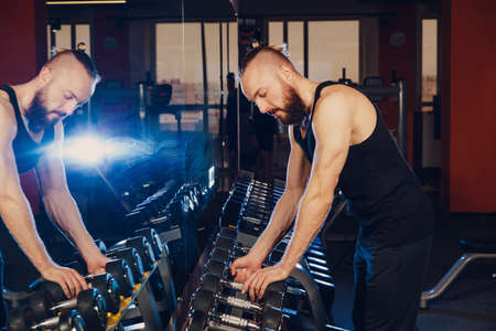 A man's hand lifts heavy dumbbells in a fitness club.の写真素材