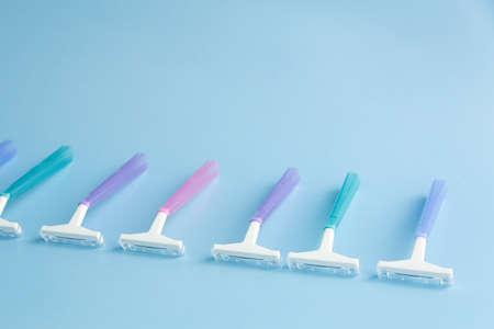 Set of multi-colored disposable razors on a blue background.の写真素材