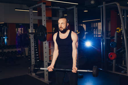 A man of athletic build is preparing to perform an exercise with a barbell.