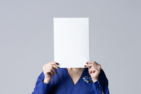 Woman covering her face with a white poster.の写真素材