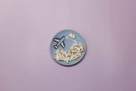 A toy plane on a purple background flying in circles with popcorn cloudsの写真素材