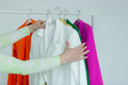 A woman's hand chooses clothes on a hanger on a white background.の写真素材