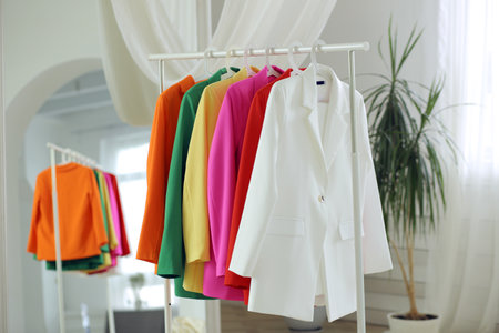 Multi-colored bright jackets on a hanger against the background of the roomの写真素材