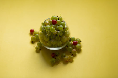 Gooseberries in a transparent jar on a yellow backgroundの写真素材