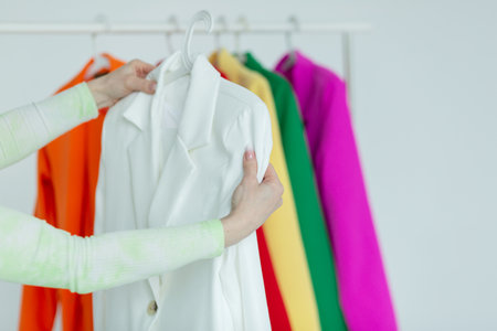 A woman's hand chooses clothes on a hanger on a white background.