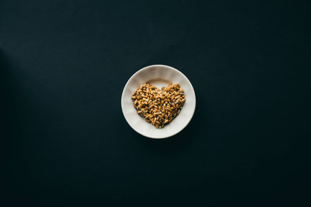 sprouted grains of wheat in shape of heart on white plate. black background with copy space. healthy food conceptの写真素材