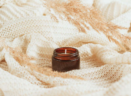 Soy wax candle in amber glass with dried flowers. Handmade candle with copy space. Beige toned photo.の写真素材