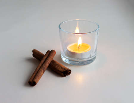 Burning little orange candle with cinnamon sticksの写真素材