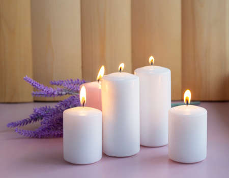 Set of white and pink burning wax candles with lavender on the wood background