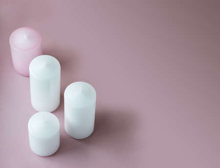 Set of white and pink wax candles on the pink background with copy space