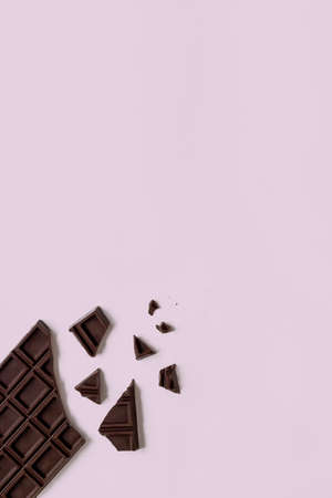 Broken chocolate bar on the pink background with copy space. Scattered chocolate pieces.の写真素材
