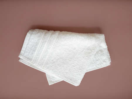 Folded white cotton towel on the beige background. bathroom accessories. top view.の写真素材