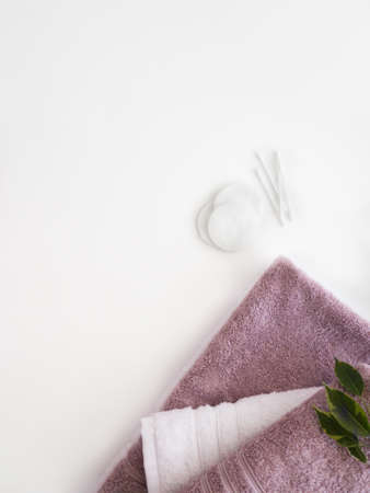 Pink and white towels with cotton pads and ear sticks on the white background. bathroom accessories. copyspace.の写真素材