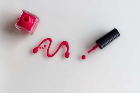 Spilled pink nail polish with bottle and brush on white backgroundの写真素材