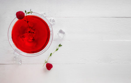 Close-up of red alcohol cocktail with raspberries and thyme on the white wood table. Top view.の写真素材