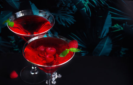 Red alcohol raspberry cocktails in martini glass on tropical background. Selective focus.の写真素材