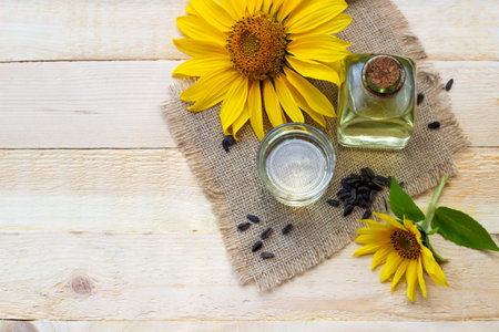 Top view of sunflower oil in a bottle glass with seeds on wooden background.の写真素材