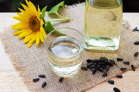 Close-up of sunflower oil in a bottle glass with seeds and sunflower on burlap canvas fabric backgroundの写真素材