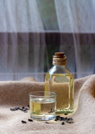 Sunflower oil in a bottle glass with seeds on burlap canvas fabric backgroundの写真素材