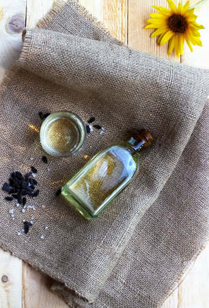 Close-up of sunflower oil in a bottle glass with seeds on burlap canvas fabric background. Top view.の写真素材