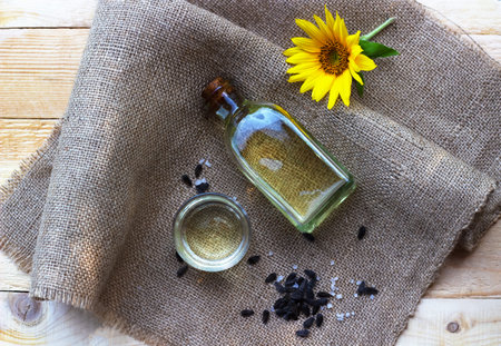 Close-up of sunflower oil in a bottle glass with seeds on burlap canvas fabric background. Top view.の写真素材