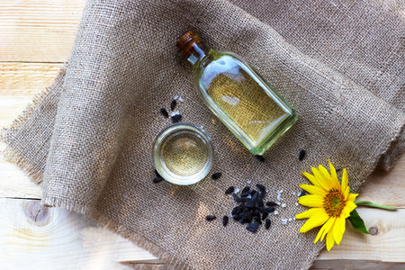 Close-up of sunflower oil in a bottle glass with seeds on burlap canvas fabric background. Top view.の写真素材