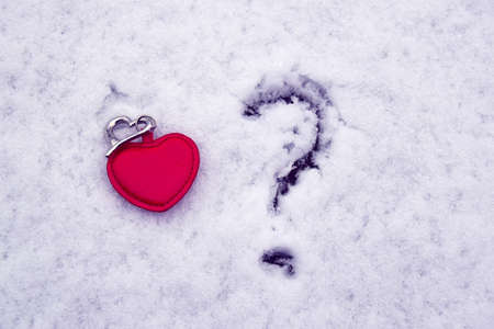 Two hearts, one red big second small silver on white sparkling snow with a question mark if there is...