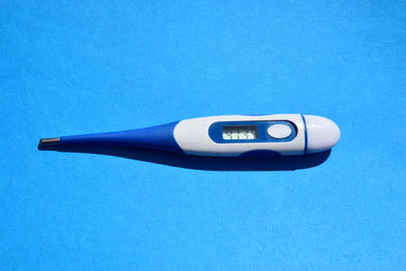 Electronic thermometer on a blue background. Top view. Health concept.の写真素材