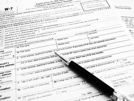 W7 tax form for US citizens, filling out a declaration and instructions. selective focus close-up. Black and white photoの写真素材